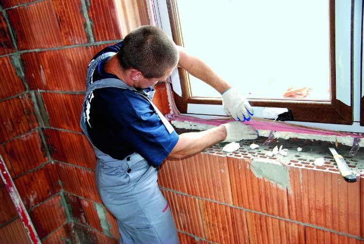 Pracownik montuje okno w budowanym domu